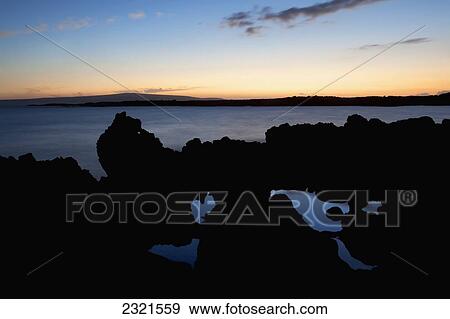 Stock Photo - Hawaii, Maui, Makena, Sunset Over Pacific Ocean, Silhouetted Lava Rock In Foreground.. Fotosearch