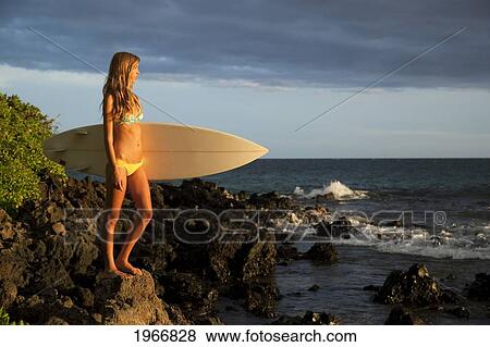 Stock Photo - Hawaii, Maui, Makena, Surfer Girl Standing On Rocks At Sunset. Fotosearch