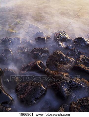 Stock Image - Hawaii, Maui, Makena, Water Flowing Over Rocks At Sunset. Fotosearch