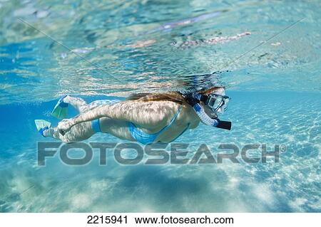 Stock Image - Hawaii, Maui, Makena, Young woman snorkles in shallow waters.. Fotosearch