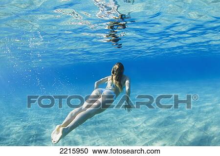 Stock Image - Hawaii, Maui, Makena, Young woman swimming near ocean surface.. Fotosearch