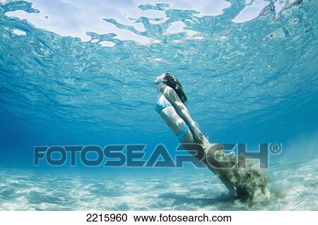 Stock Image - Hawaii, Maui, Makena, Young woman swimming to ocean surface, Creating sand cloud behind her. Fotosearch