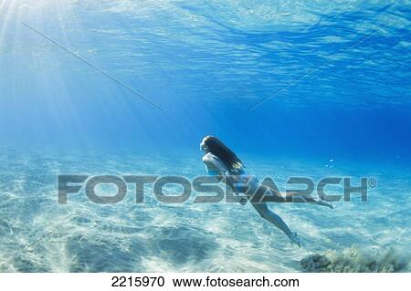 Stock Image - Hawaii, Maui, Makena, Young woman enjoys a swim in the ocean.. Fotosearch
