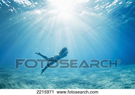 Stock Image - Hawaii, Maui, Makena, Young woman enjoys a swim in the ocean.. Fotosearch
