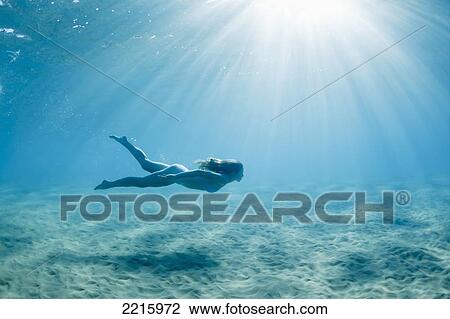 Stock Image - Hawaii, Maui, Makena, Young woman enjoys a swim in the ocean.. Fotosearch