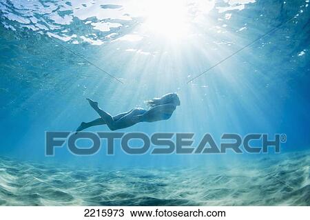 Stock Image - Hawaii, Maui, Makena, Young woman enjoys a swim in the ocean.. Fotosearch