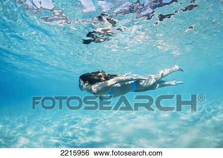 Stock Photograph - Hawaii, Maui, Makena, Young woman swimming near ocean surface.. Fotosearch