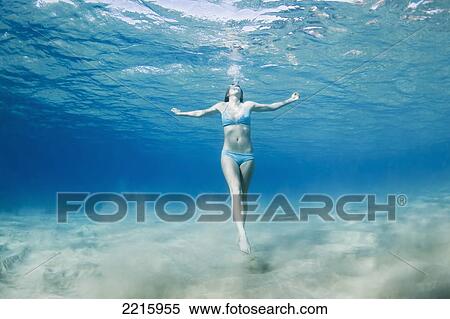 Stock Photography - Hawaii, Maui, Makena, Young woman swimming near ocean surface, View from below.. Fotosearch