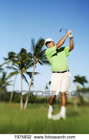 Stock Image - Hawaii, Maui, Male Golfer Swinging Golf Club At The Maui Country Club Course.. Fotosearch