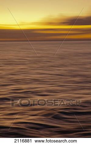 Stock Image - Hawaii, Maui, Ocean waves in motion and a vibrant tropical sunset.. Fotosearch
