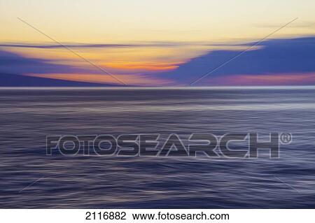 Stock Image - Hawaii, Maui, Ocean waves in motion and a vibrant tropical sunset.. Fotosearch