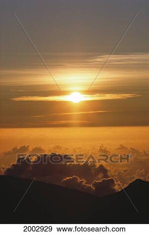 Stock Photo - Hawaii, Maui, Orange Sun Ball Sunrise From Haleakala Crater Summit Moody Gray Cloud Streaks. Fotosearch