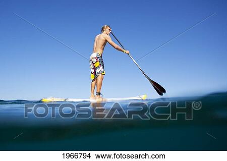 Picture - Hawaii, Maui, Paia, Athletic Stand Up Paddle Surfer In Maui's North Shore, Over-Under Shot. Fotosearch