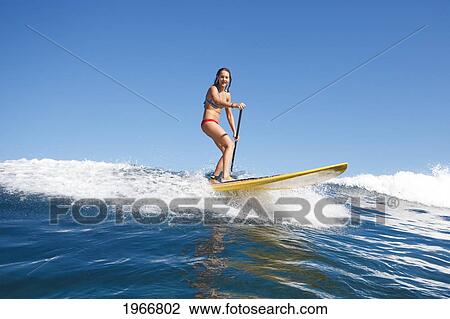 Stock Image - Hawaii, Maui, Paia, Female Stand Up Paddle Boarder Rides A Wave On Maui's North Shore/Nno Commercial Use. Fotosearch