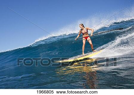 Stock Photography - Hawaii, Maui, Paia, Female Stand Up Paddle Boarder Rides A Wave On Maui's North Shore/Nno Commercial Use. Fotosearch