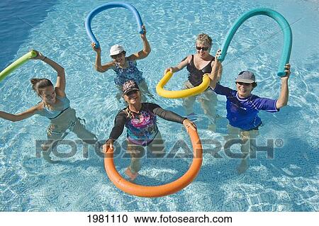 Stock Image - Hawaii, Maui, Paia, Maui Country Club, Aquasize Class, Smiling Women Demonstrating Move With Colorful Devices.. Fotosearch