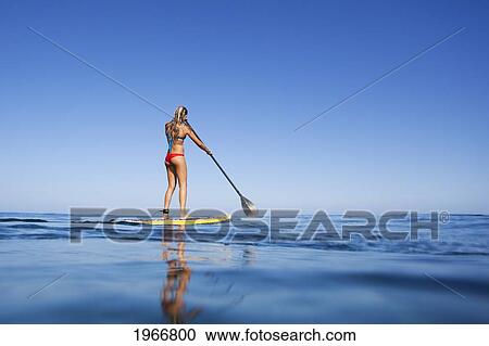 Stock Image - Hawaii, Maui, Paia, Young Woman Stand Up Paddling Shore/N/Nno Commercial Use. Fotosearch