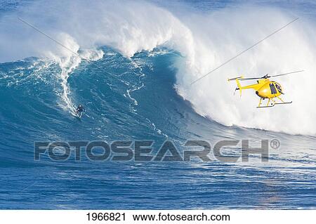 Stock Image - Hawaii, Maui, Peahi (Jaws), Helicopter, Surfer Rides A Giant Wave. Fotosearch