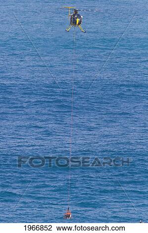 Stock Image - Hawaii, Maui, Peahi (Jaws), Helicopter Carries Basket With Rescue Divers. Fotosearch
