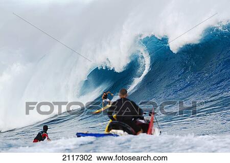 Stock Image - Hawaii, Maui, Peahi, Surfer rides a giant wave at Peahi also know as Jaws with lifeguards ready for safety. EDITORIAL USE ONLY.. Fotosearch