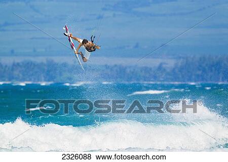 Stock Photo - Hawaii, Maui, Professional Kiteboarder Niccolo Porcella Catching Air Off The North Shore, Ocean Spray In The Foreground. Editorial Use Only.. Fotosearch