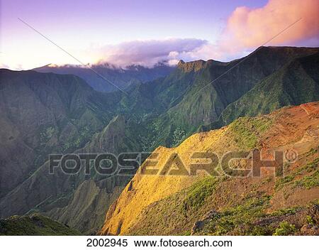 Stock Photography - Hawaii, Maui, Ukumehame Gulch And West Maui Mountains At Sunset, Orange Cloud, With Green Mountains In Background.. Fotosearch