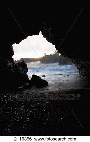 Stock Photograph - Hawaii, Maui, Waianapanapa, Watching the sunrise from a lava cave.. Fotosearch