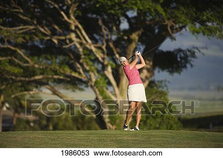 Stock Image - Hawaii, Maui, Wailea Gold Golf Course, Female Golfer Swinging Golf Club.. Fotosearch