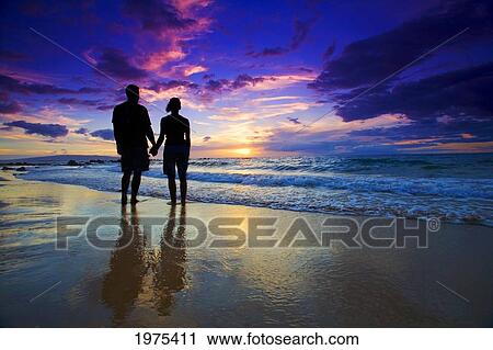 Stock Image - Hawaii, Maui, Wailea, Mokapu Beach, Silhouetted Couple Watching Sunset.. Fotosearch
