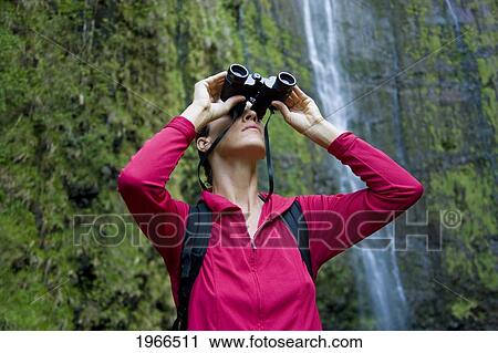 Stock Image - Hawaii, Maui, Waimoku Falls, Female Hiker Using Binoculars.. Fotosearch