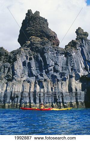 Stock Photo - Hawaii, Maui, Woman Kayaking Past Dramatic Cliffs And Rock Formations. Fotosearch