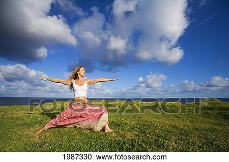 Stock Image - Hawaii, Maui, Young Woman Doing Yoga On Grassy Hill Next To The Ocean.. Fotosearch