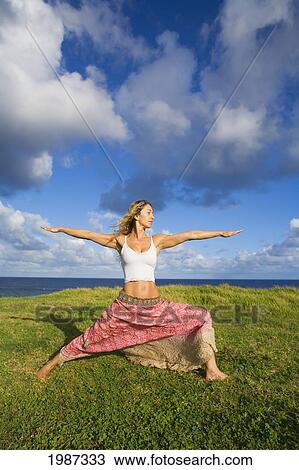Stock Image - Hawaii, Maui, Young Woman Doing Yoga On Grassy Hill Next To The Ocean.. Fotosearch