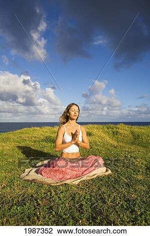 Stock Image - Hawaii, Maui, Young Woman Doing Yoga On Grassy Hill Next To The Ocean.. Fotosearch