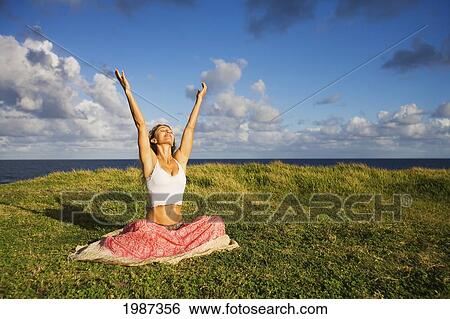 Stock Photograph - Hawaii, Maui, Young Woman Doing Yoga On Grassy Hill Next To The Ocean.. Fotosearch