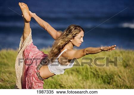 Stock Photography - Hawaii, Maui, Young Woman Doing Yoga On Grassy Hill Next To The Ocean.. Fotosearch