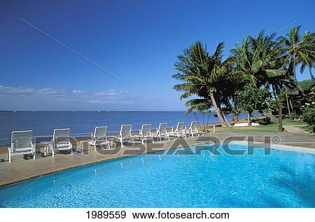 Stock Photo - Hawaii, Molokai, Hotel Molokai Pool With Palm Trees, Looking Out To Ocean, Blue Sky.. Fotosearch