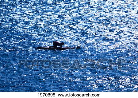 Stock Photo - Hawaii, Molokai, Man Kneeling On A Paddleboard.. Fotosearch