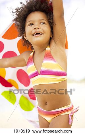 Stock Photo - Hawaii, Oahu, Adorable Little Girl Holding A Polka-Dot Towel Along The Waters Edge.. Fotosearch