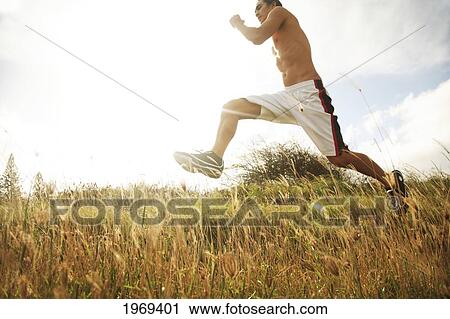 Stock Image - Hawaii, Oahu, Atheltic Male Jogging On An Outdoor Field Walkway Path. Fotosearch
