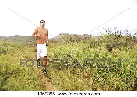 Stock Photograph - Hawaii, Oahu, Atheltic Male Jogging On An Outdoor Field Walkway Path. Fotosearch