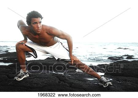 Stock Image - Hawaii, Oahu, Athletic Male Excercising On The Beach.. Fotosearch