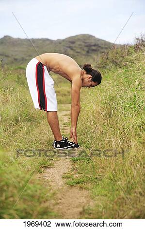 Stock Image - Hawaii, Oahu, Athletic Male Runner Stretching On A Jogging Path.. Fotosearch