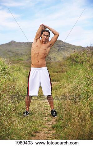 Stock Image - Hawaii, Oahu, Athletic Male Runner Stretching On A Jogging Path.. Fotosearch