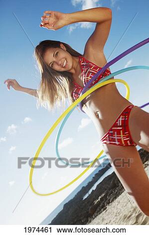 Stock Image - Hawaii, Oahu, Attractive Young Woman On The Beach Hula Hooping.. Fotosearch