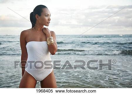 Stock Photography - Hawaii, Oahu, Attractive Young Woman On The Shoreline With Gold Bracelets.. Fotosearch