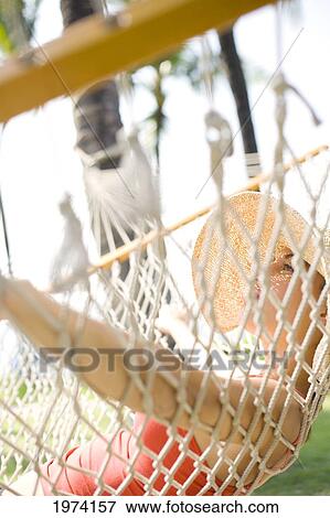 Stock Photo - Hawaii, Oahu, Attractive Young Woman Laying In A Hammock.. Fotosearch