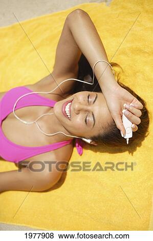 Hawaii, Oahu, Attractive Young Woman Laying On A Towel On Beach, Sunbathing And Listening To Ipod. View Large Photo Image Stock Photo - Hawaii, Oahu, Attractive Young Woman Laying On A Towel On Beach, Sunbathing And Listening To Ipod.. Fotosearch