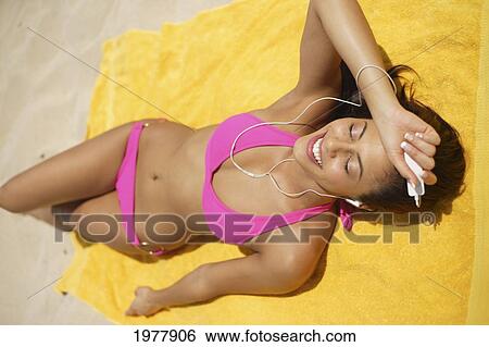 Hawaii, Oahu, Attractive Young Woman Laying On A Towel On Beach, Sunbathing And Listening To Ipod. View Large Photo Image Stock Photograph - Hawaii, Oahu, Attractive Young Woman Laying On A Towel On Beach, Sunbathing And Listening To Ipod.. Fotosearch