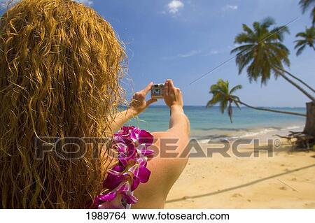 Picture - Hawaii, Oahu, Beautiful Young Woman Photographing Tropical Beach With Lei.. Fotosearch